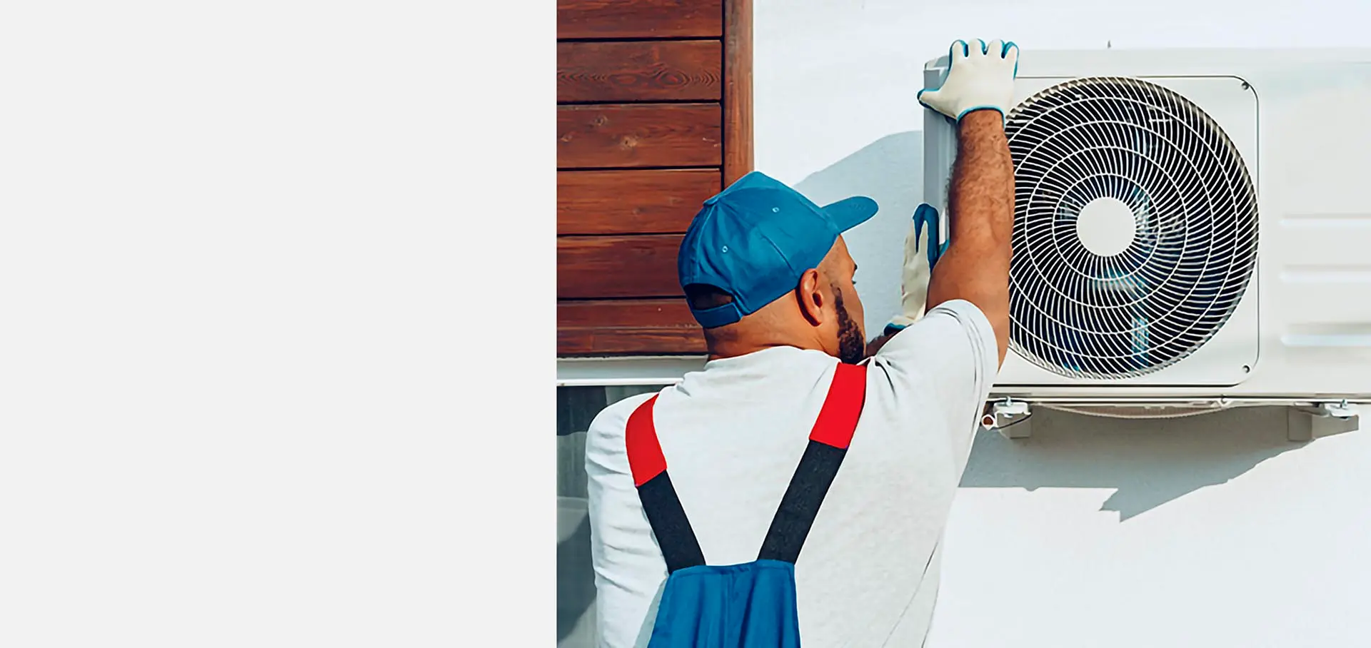 Technician installing an air conditioner on a house wall