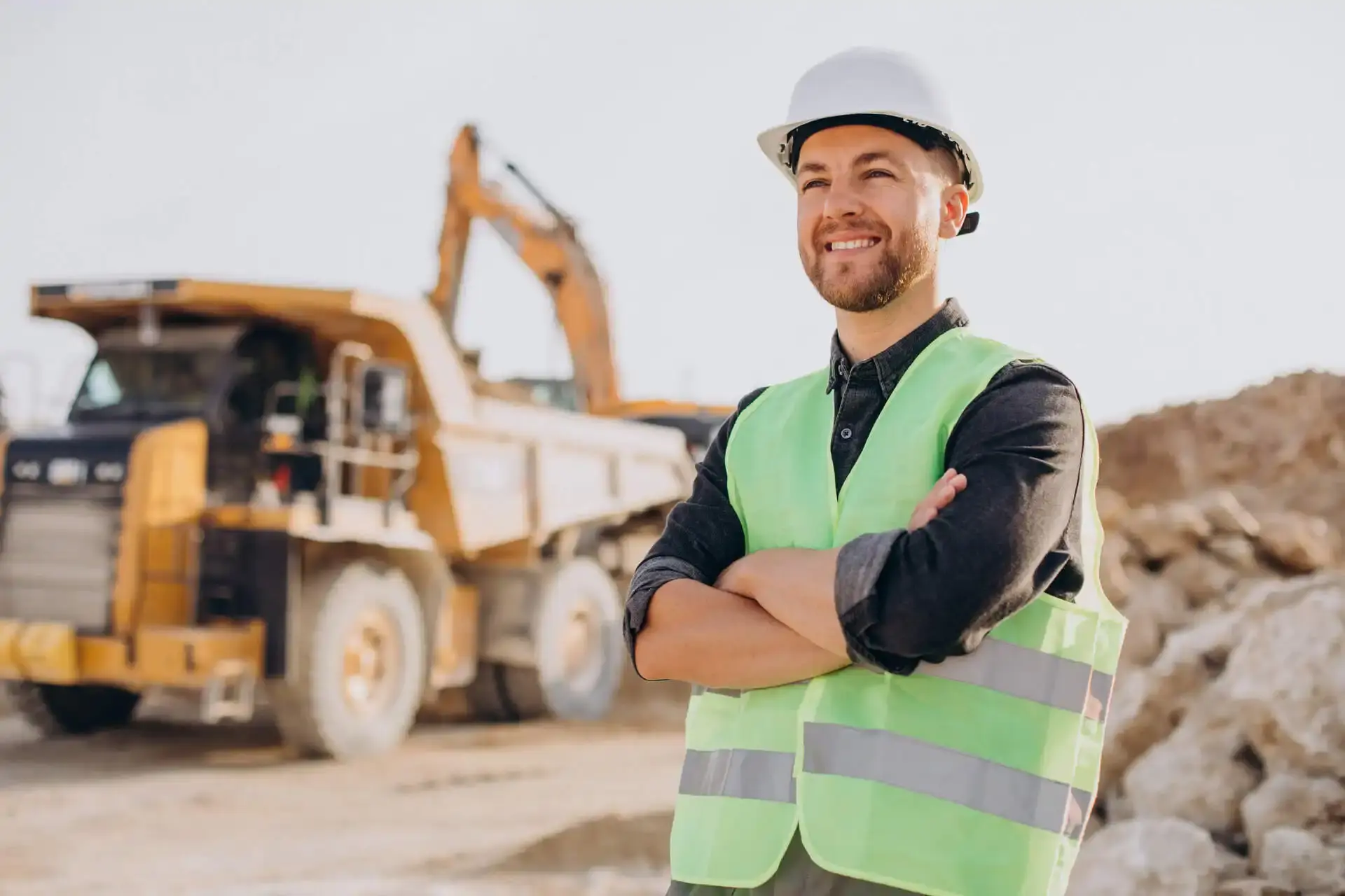 Smiling worker in a hard hat and vest near quarry machinery