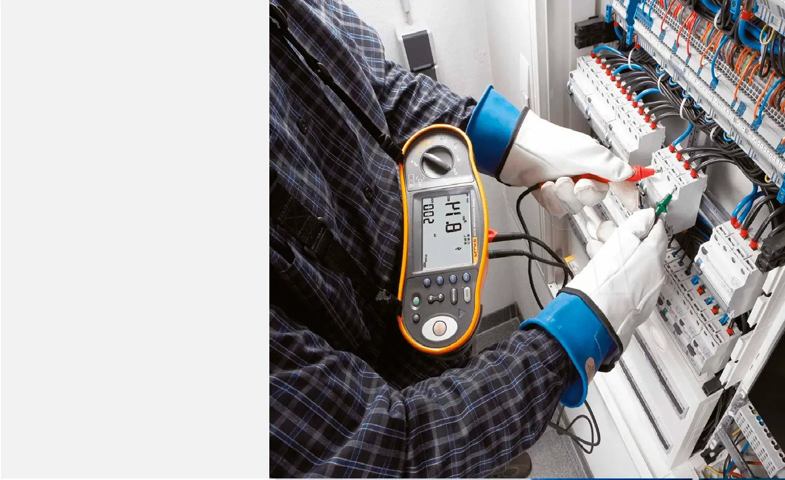 Electrician measuring with a clamp meter at an electrical panel